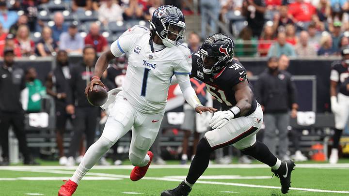 Sep 28, 2025; Houston, Texas, USA; Tennessee Titans quarterback Cam Ward (1) scrambles from Houston Texans defensive end Will Anderson Jr. (51) during the first half at NRG Stadium. Mandatory Credit: Troy Taormina-Imagn Images