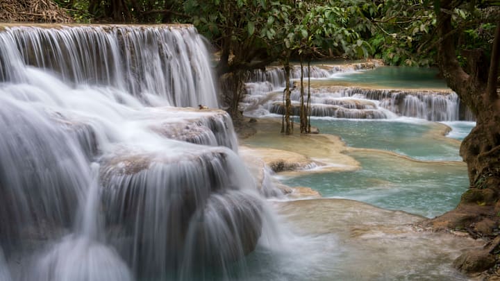 Cascades and turquoise blue pools of the Kuang Si Falls near...