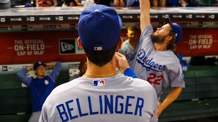Aug 10, 2017; Phoenix, AZ, USA; Los Angeles Dodgers first baseman Cody Bellinger (35) autographs a ball and tosses it to a fan as pitcher Clayton Kershaw leaps to block it prior to the game against the Arizona Diamondbacks at Chase Field. Mandatory Credit: Mark J. Rebilas-Imagn Images