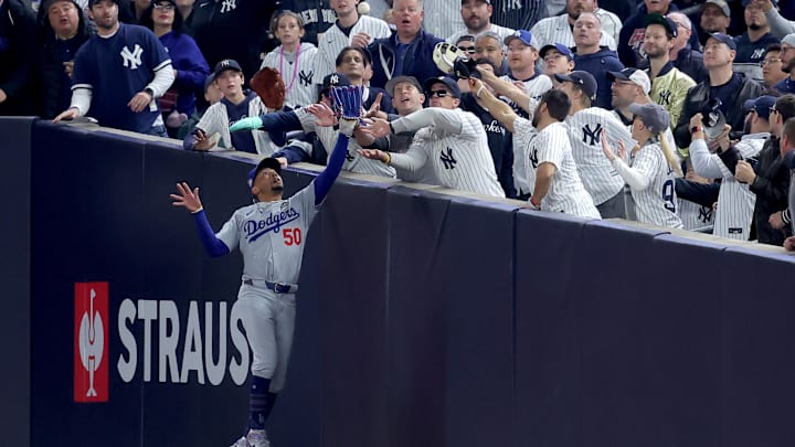 Oct 29, 2024; New York, New York, USA; Los Angeles Dodgers shortstop Mookie Betts (50) makes a catch in foul territory as a New York Yankees fan interferes during the first inning in game four of the 2024 MLB World Series at Yankee Stadium. Oct 29, 2024; New York, New York, USA; Los Angeles Dodgers shortstop Mookie Betts (50) makes a catch in foul territory as a New York Yankees fan interferes during the first inning in game four of the 2024 MLB World Series at Yankee Stadium.