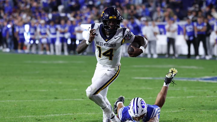 Oct 3, 2025; Provo, Utah, USA; West Virginia Mountaineers quarterback Khalil Wilkins (14) breaks a tackle by Brigham Young Cougars linebacker Siale Esera (54) during the third quarter at LaVell Edwards Stadium. Mandatory Credit: Rob Gray-Imagn Images