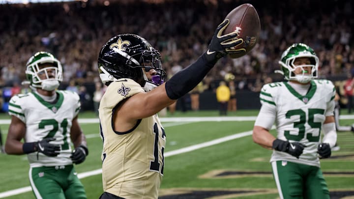 Dec 21, 2025; New Orleans, Louisiana, USA; New Orleans Saints wide receiver Chris Olave (12) crosses the goal line for a touchdown against New York Jets cornerback Brandon Stephens (21) and safety Dean Clark (35) during the third quarter at Caesars Superdome. Mandatory Credit: Matthew Hinton-Imagn Images