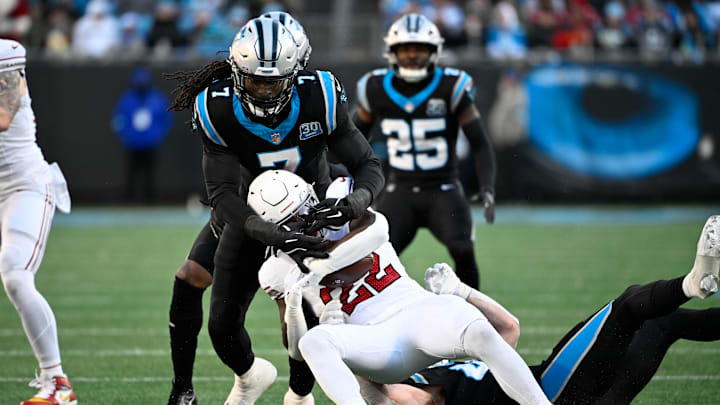 Dec 22, 2024; Charlotte, North Carolina, USA; Arizona Cardinals running back Michael Carter (22) is tackled by Carolina Panthers linebacker Jadeveon Clowney (7) in the third quarter at Bank of America Stadium. Mandatory Credit: Bob Donnan-Imagn Images