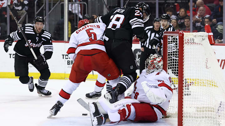 Dec 27, 2024; Newark, New Jersey, USA; Carolina Hurricanes defenseman Jalen Chatfield (5) and New Jersey Devils right wing Timo Meier (28) battle for the puck in front of Carolina Hurricanes goaltender Pyotr Kochetkov (52) during the second period at Prudential Center. Mandatory Credit: Ed Mulholland-Imagn Images