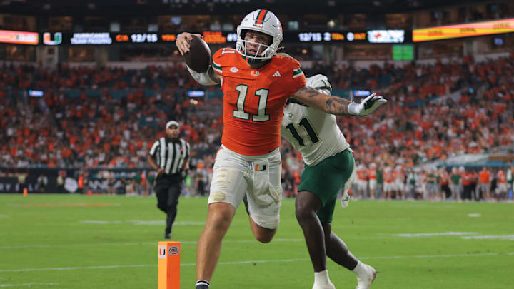 Sep 13, 2025; Miami Gardens, Florida, USA; Miami Hurricanes quarterback Carson Beck (11) carries the football for a touchdown against South Florida Bulls fullback D.J. Harris (11) during the second quarter at Hard Rock Stadium. Mandatory Credit: Sam Navarro-Imagn Images