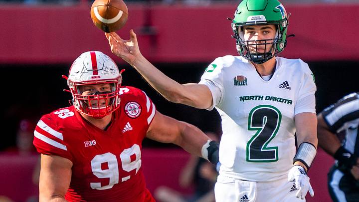 North Dakota Fighting Hawks quarterback passes as a Nebraska Cornhuskers defensive lineman rushes the passer