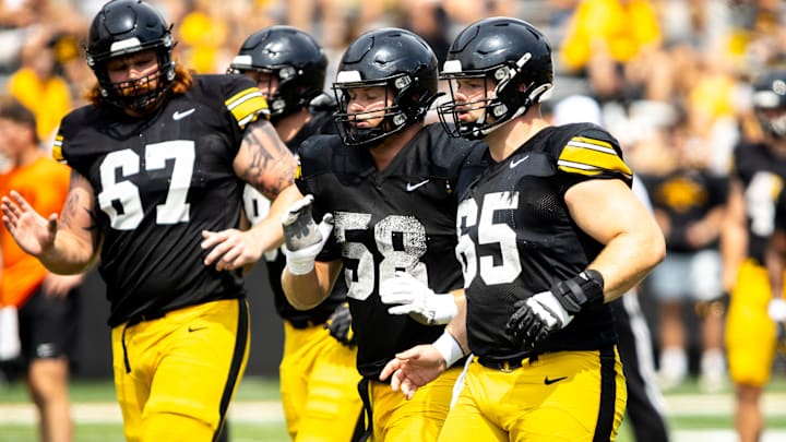 Aug 9, 2025; Iowa offensive linemen Gennings Dunker (67) Kade Pieper (58) and Logan Jones (65) run a drill during the Hawkeyes Kids Day NCAA football open practice at Kinnick Stadium in Iowa City, Iowa. Mandatory Credit: Joseph Cress for the Des Moines Register
