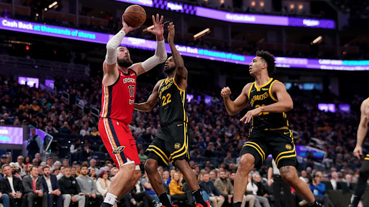 Jan 10, 2024; San Francisco, California, USA; New Orleans Pelicans center Jonas Valanciunas (17) holds onto the ball next to Golden State Warriors forward Andrew Wiggins (22) and forward Trayce Jackson-Davis (32) in the third quarter at the Chase Center. Mandatory Credit: Cary Edmondson-Imagn Images