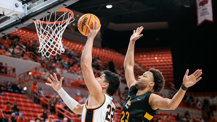 Dec 29, 2025; Stillwater, Oklahoma, USA; Oklahoma State Cowboys forward Parsa Fallah (22) shoots the ball around Bethune-Cookman Wildcats forward Daniel Rouzan (23) during the first half at Gallagher-Iba Arena. Mandatory Credit: William Purnell-Imagn Images