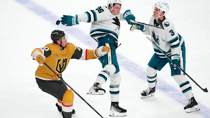 Oct 26, 2024; Las Vegas, Nevada, USA; San Jose Sharks defenseman Jack Thompson (26) bats down the puck between Vegas Golden Knights left wing Tanner Pearson (70) and San Jose Sharks defenseman Henry Thrun (3) during the third period at T-Mobile Arena. Mandatory Credit: Stephen R. Sylvanie-Imagn Images