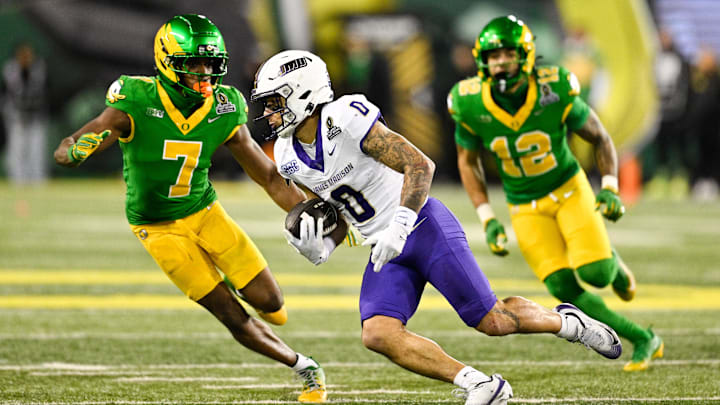 Dec 20, 2025; Eugene, OR, USA; James Madison Dukes wide receiver Jaylan Sanchez (0) runs after making a catch as Oregon Ducks defensive back Ify Obidegwu (7) defends during the fourth quarter at Autzen Stadium. Mandatory Credit: Troy Wayrynen-Imagn Images Dec 20, 2025; Eugene, OR, USA; James Madison Dukes wide receiver Jaylan Sanchez (0) runs after making a catch as Oregon Ducks defensive back Ify Obidegwu (7) defends during the fourth quarter at Autzen Stadium. Mandatory Credit: Troy Wayrynen-Imagn Images