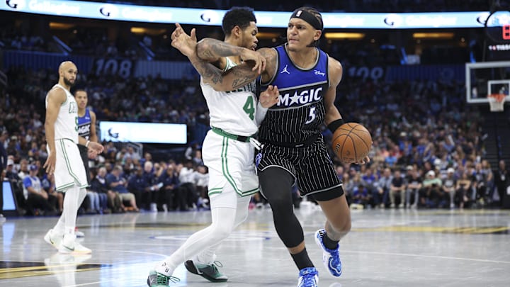 Nov 7, 2025; Orlando, Florida, USA; Orlando Magic forward Paolo Banchero (5) is guarded by Boston Celtics guard Anfernee Simons (4) in the fourth quarter  at Kia Center. Mandatory Credit: Nathan Ray Seebeck-Imagn Images