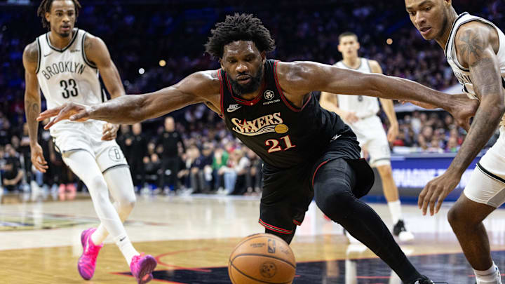 Dec 23, 2025; Philadelphia, Pennsylvania, USA; Philadelphia 76ers center Joel Embiid (21) lunges for a loose ball in front of Brooklyn Nets forward Noah Clowney (21) during the fourth quarter at Xfinity Mobile Arena. Mandatory Credit: Bill Streicher-Imagn Images