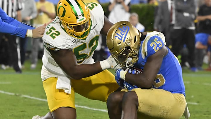 Sep 28, 2024; Pasadena, California, USA; Oregon Ducks defensive lineman A'Mauri Washington (52) tackles UCLA Bruins running back T.J. Harden (25) in the backfield during the third quarter at Rose Bowl. Mandatory Credit: Robert Hanashiro-Imagn Images
