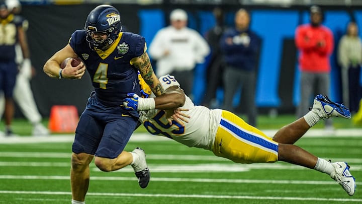 Toledo Rockets quarterback Tucker Gleason (4) avoids being tackled by Pittsburgh Panthers defensive lineman Francis Brewu (95), during one of the six overtimes in the 2024 GameAbove Sports Bowl at Ford Field in Detroit, on Thursday, Dec. 26, 2024.