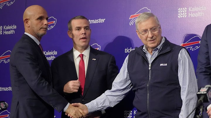 Pete Guelli, president of business operations, Brandon Beane, president of football operations and general manager, shake hands with owner and president Terry Pegula after a group photo with new Bills head coach Joe Brady on Jan. 29, 2026