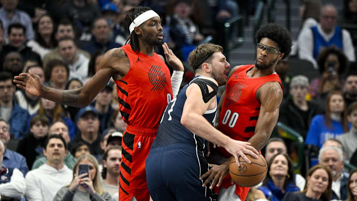 Jan 3, 2024; Dallas, Texas, USA; Dallas Mavericks guard Luka Doncic (77) is fouled as he drives to the basket between Portland Trail Blazers forward Jerami Grant (9) and guard Scoot Henderson (00) during the first quarter at the American Airlines Center. Mandatory Credit: Jerome Miron-Imagn Images Jan 3, 2024; Dallas, Texas, USA; Dallas Mavericks guard Luka Doncic (77) is fouled as he drives to the basket between Portland Trail Blazers forward Jerami Grant (9) and guard Scoot Henderson (00) during the first quarter at the American Airlines Center. Mandatory Credit: Jerome Miron-Imagn Images