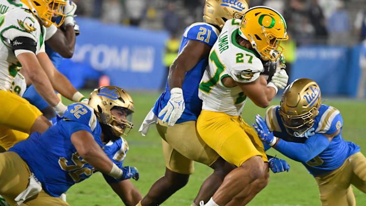 Sep 28, 2024; Pasadena, California, USA; UCLA Bruins defensive lineman Siale Taupaki (92), linebacker JonJon Vaughns (21), and defensive back Kaylin Moore (9) tackles Oregon Ducks running back Jayden Limar (27) during the fourth quarter at Rose Bowl. Mandatory Credit: Robert Hanashiro-Imagn Images