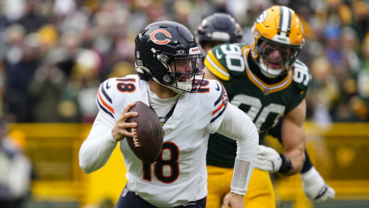 Jan 5, 2025; Green Bay, Wisconsin, USA;  Chicago Bears quarterback Caleb Williams (18) scrambles away from pressure applied by Green Bay Packers defensive lineman Lukas Van Ness (90) during the first quarter at Lambeau Field. Mandatory Credit: Jeff Hanisch-Imagn Images