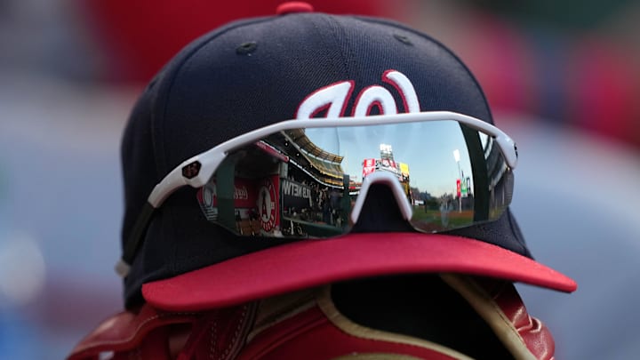 May 7, 2022; Anaheim, California, USA; A detailed view of a Washington Nationals cap and glove with sunglasses in the dugout before a game against the Los Angeles Angels at Angel Stadium. 