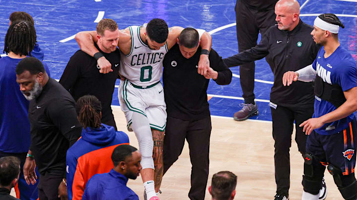 May 12, 2025; New York, New York, USA; Boston Celtics forward Jayson Tatum (0) is helped off the court by after an injury in the second half during game four of the second round for the 2025 NBA Playoffs against the New York Knicks at Madison Square Garden. Tatum would leave the game with an injury after this play. Mandatory Credit: Vincent Carchietta-Imagn Images