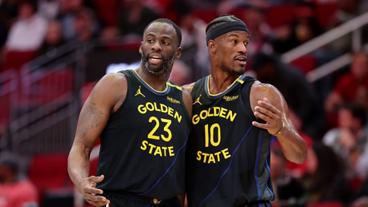 Draymond Green #23 and Jimmy Butler #10 of the Golden State Warriors speak on the court against the Houston Rockets during the first half at Toyota Center on February 13, 2025 in Houston, Texas.