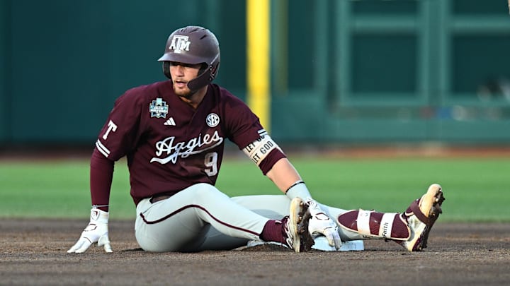 Jun 19, 2024; Omaha, NE, USA;  Texas A&M Aggies third baseman Gavin Grahovac (9) sits on the base after being thrown out against the Florida Gators during the second inning at Charles Schwab Field Omaha. Mandatory Credit: Steven Branscombe-Imagn Images