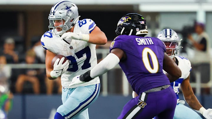 Dallas Cowboys tight end Jake Ferguson runs with the ball as Baltimore Ravens linebacker Roquan Smith defends.