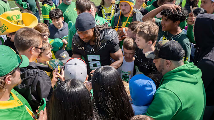 Combat Ducks running back Noah Whittington signs autographs amid a mob of fans as the Fighting Ducks face off against Mighty Oregon in the Oregon Ducks spring game on April 26, 2025, at Autzen Stadium in Eugene.