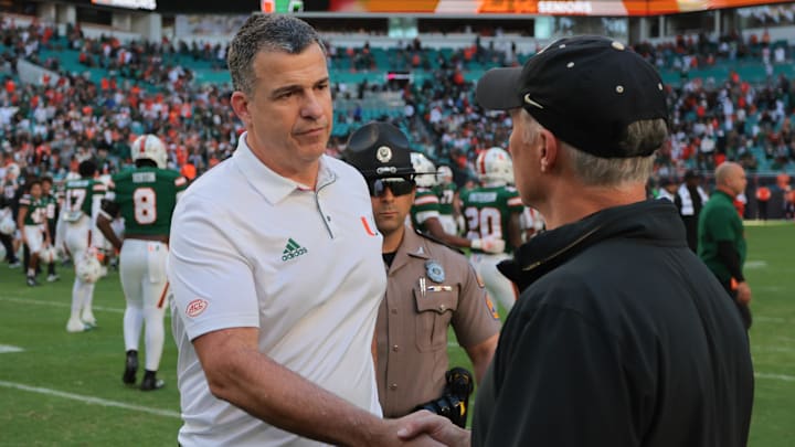 Nov 23, 2024; Miami Gardens, Florida, USA; Miami Hurricanes head coach Mario Cristobal shakes hands with Wake Forest Demon Deacons head coach Dave Clawson after the game at Hard Rock Stadium. Mandatory Credit: Sam Navarro-Imagn Images