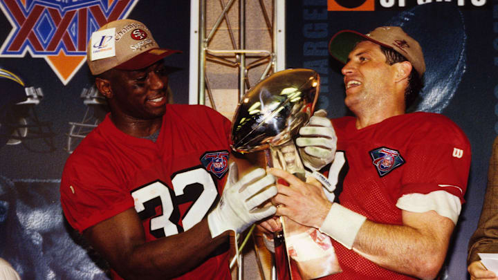 San Francisco quarterback Steve Young (8) holds the Lombardi trophy with running back Ricky Watters (32)