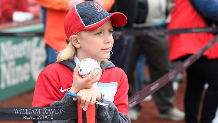 A young Boston Red Sox fan waits for players to walk by in hopes of getting a ball autographed before a game against the San Francisco Giants at Fenway Park.