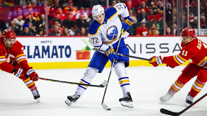 Jan 23, 2025; Calgary, Alberta, CAN; Buffalo Sabres center Tage Thompson (72) controls the puck against Calgary Flames center Mikael Backlund (11) and defenseman Kevin Bahl (7) during the first period at Scotiabank Saddledome. Mandatory Credit: Sergei Belski-Imagn Images