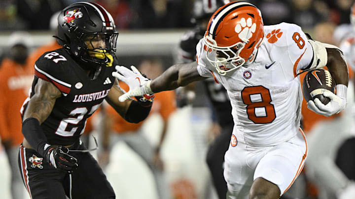 Nov 14, 2025; Louisville, Kentucky, USA; Clemson Tigers running back Adam Randall (8) runs the ball against Louisville Cardinals defensive back Jojo Evans Jr. (27) during the first half at L&N Federal Credit Union Stadium. Clemson defeated Louisville 20-19. Mandatory Credit: Jamie Rhodes-Imagn Images