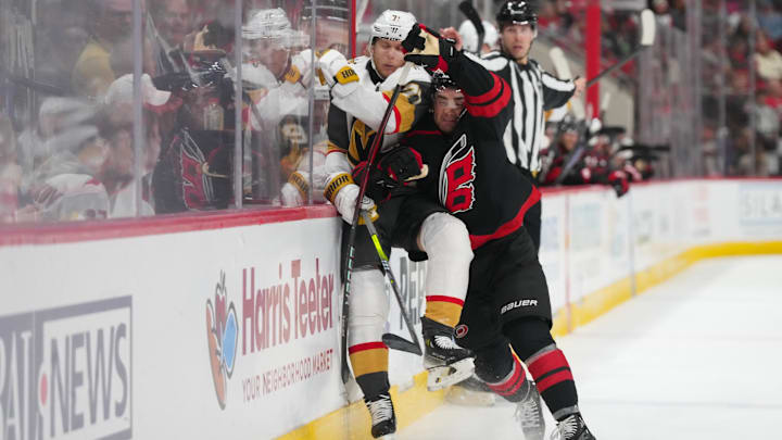 Oct 28, 2025; Raleigh, North Carolina, USA;  Carolina Hurricanes defenseman Sean Walker (26) checks Vegas Golden Knights center William Karlsson (71) during the second period at Lenovo Center. Mandatory Credit: James Guillory-Imagn Images