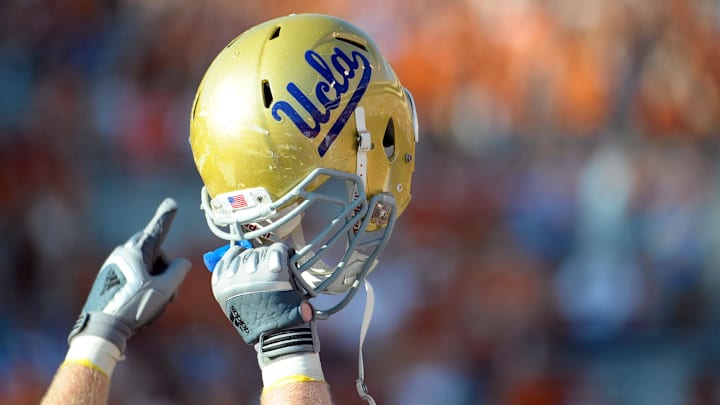 Sept 25, 2010; Austin, TX, USA; A member of the UCLA Bruins holds up his helmet to acknowledge their fans against the Texas Longhorns during the fourth quarter at Texas Memorial Stadium. UCLA beat Texas 34-12. Mandatory Credit: Brendan Maloney-Imagn Images
