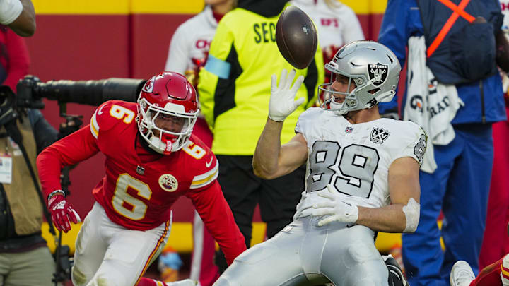 Nov 29, 2024; Kansas City, Missouri, USA; Las Vegas Raiders tight end Brock Bowers (89) tosses the ball after scoring a touchdown against Kansas City Chiefs safety Bryan Cook (6) during the second half at GEHA Field at Arrowhead Stadium. Mandatory Credit: Jay Biggerstaff-Imagn Images
