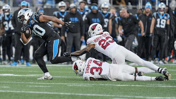 Dec 22, 2024; Charlotte, North Carolina, USA; Carolina Panthers running back Chuba Hubbard (30) avoids tackle by Arizona Cardinals cornerback Starling Thomas V (24) and cornerback Sean Murphy-Bunting (23) in overtime to win the game during the second half at Bank of America Stadium. Mandatory Credit: Jim Dedmon-Imagn Images