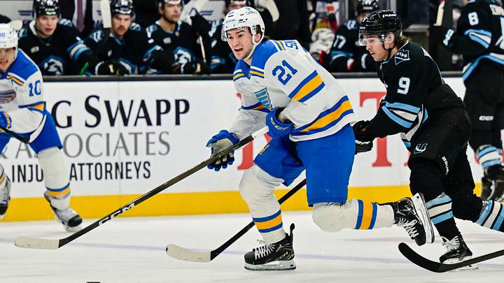 Jan 9, 2026; Salt Lake City, Utah, USA; St. Louis Blues right wing Jimmy Snuggerud (21) lines up his next shot ahead of Utah Mammoth right wing Clayton Keller (9) during third period at Delta Center. Mandatory Credit: Peter Creveling-Imagn Images