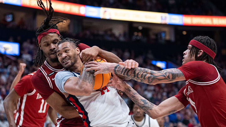 Arkansas Razorbacks forward Jonas Aidoo (9) guards Ole Miss Rebels guard Dre Davis (14) while Arkansas Razorbacks guard Trevon Brazile (4) defends during their second round game of the SEC Men's Basketball Tournament at Bridgestone Arena in Nashville.