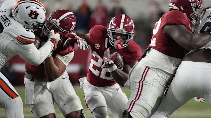 Nov 30, 2024; Tuscaloosa, Alabama, USA;  Alabama Crimson Tide running back Justice Haynes (22) runs behind offensive lineman Parker Brailsford (72) and offensive lineman Tyler Booker (52) against the Auburn Tigers during the second half at Bryant-Denny Stadium. Alabama won 28-14. Mandatory Credit: Gary Cosby Jr.-Imagn Images