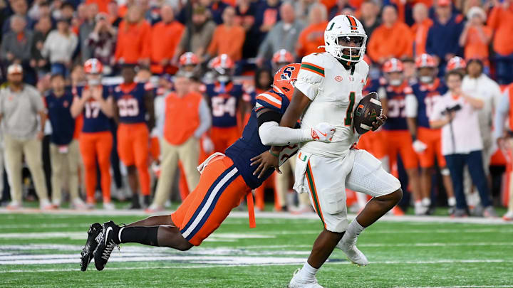 Nov 30, 2024; Syracuse, New York, USA; Miami Hurricanes quarterback Cam Ward (1) runs with the ball as Syracuse Orange linebacker Marlowe Wax (left) attempts to make a tackle during the second half at the JMA Wireless Dome. Mandatory Credit: Rich Barnes-Imagn Images