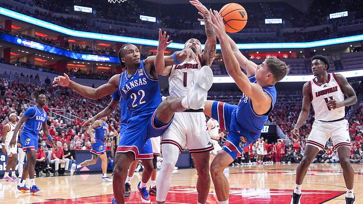 Kansas Jayhawks guard Darryn Peterson (22) and Kansas Jayhawks guard Kohl Rosario (7) surround Louisville Cardinals guard J'Vonne Hadley (1) as the trio battle for a loose ball during an exhibition game at the KFC Yum! Center in Louisville, Kentucky Friday, October 24, 2025.