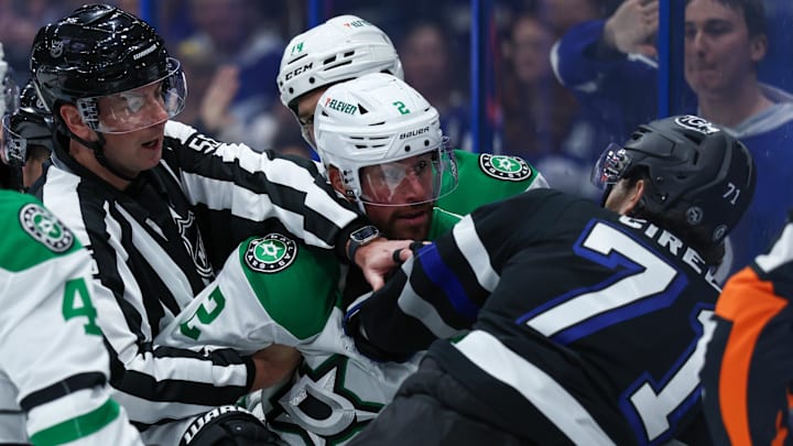 Nov 23, 2024; Tampa, Florida, USA; Tampa Bay Lightning center Anthony Cirelli (71) and Dallas Stars defenseman Brendan Smith (2) are separated by linesman Kyle Flemington (55) in the first period at Amalie Arena. Mandatory Credit: Nathan Ray Seebeck-Imagn Images