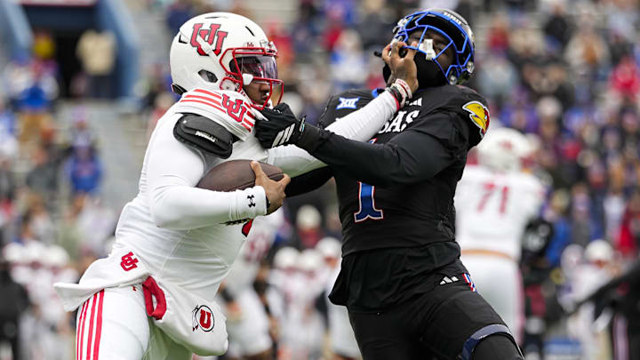 Nov 28, 2025; Lawrence, Kansas, USA; Utah Utes quarterback Devon Dampier (4) stiff arms Kansas Jayhawks linebacker Bangally Kamara (1) during the second half at David Booth Kansas Memorial Stadium. Mandatory Credit: Jay Biggerstaff-Imagn Images
