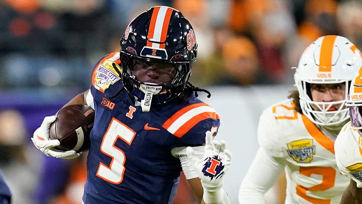 Illinois running back Ca'Lil Valentine (5) runs the ball ahead of Tennessee defensive back Andre Turrentine (2) and linebacker Jadon Perlotte (27) for a first down in the first quarter of the Music City Bowl against Tennessee in an NCAA football game on Dec. 30, 2025, in Nashville, Tennessee.