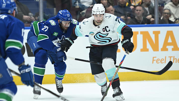 Vancouver Canucks defenseman Derek Forbort (27) checks Seattle Kraken forward Jordan Eberle (7).