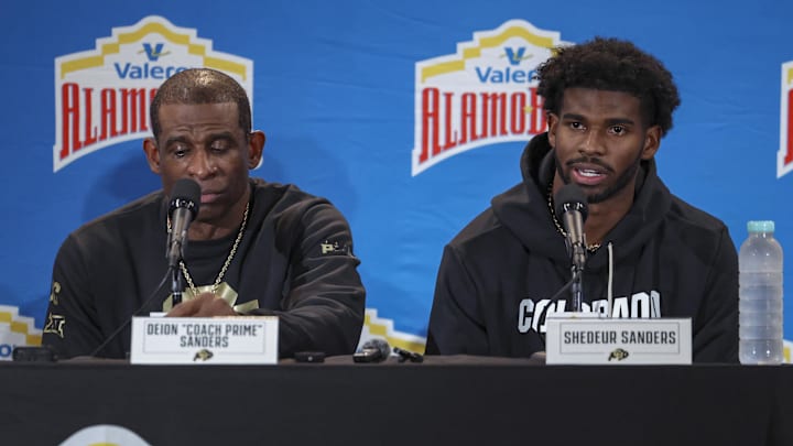 Dec 28, 2024; San Antonio, TX, USA; Colorado Buffaloes head coach Deion Sanders and quarterback Shedeur Sanders (2) talk with the media after the game against the Brigham Young Cougars at Alamodome. Mandatory Credit: Troy Taormina-Imagn Images