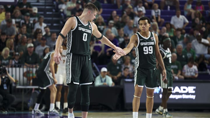 Nov 25, 2025; Fort Myers, Florida, USA; Michigan State Spartans forward Jaxon Kohler (0) and guard Divine Ugochukwu (99) react after a three point basket against the East Carolina Pirates in the second half at Suncoast Credit Union Arena. Mandatory Credit: Nathan Ray Seebeck-Imagn Images Nov 25, 2025; Fort Myers, Florida, USA; Michigan State Spartans forward Jaxon Kohler (0) and guard Divine Ugochukwu (99) react after a three point basket against the East Carolina Pirates in the second half at Suncoast Credit Union Arena. Mandatory Credit: Nathan Ray Seebeck-Imagn Images
