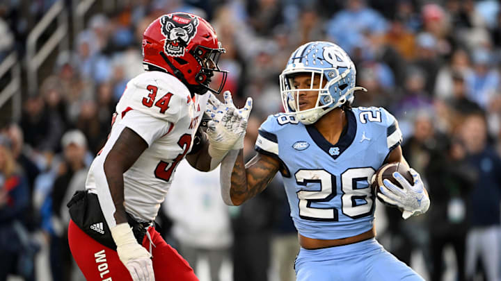 Nov 30, 2024; Chapel Hill, North Carolina, USA; North Carolina Tar Heels running back Omarion Hampton (28) with the ball as North Carolina State Wolfpack linebacker Kamal Bonner (34) defends in the first quarter at Kenan Memorial Stadium. Mandatory Credit: Bob Donnan-Imagn Images Nov 30, 2024; Chapel Hill, North Carolina, USA; North Carolina Tar Heels running back Omarion Hampton (28) with the ball as North Carolina State Wolfpack linebacker Kamal Bonner (34) defends in the first quarter at Kenan Memorial Stadium. Mandatory Credit: Bob Donnan-Imagn Images